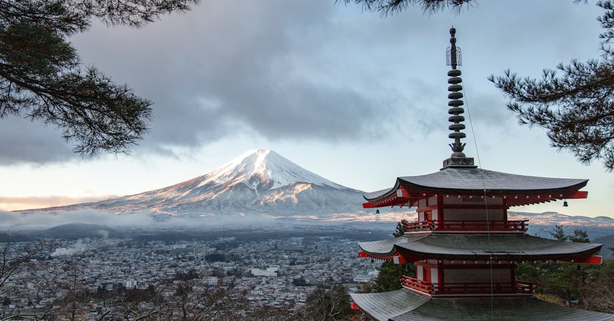 Scenic view of Chureito Pagoda with snow-capped Mount Fuji under a cloudy sky in Fujinomiya, Japan.