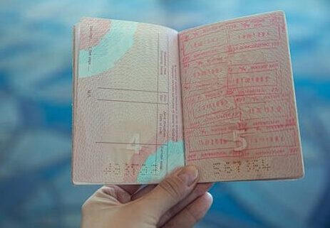 Close-up view of an open passport displaying various travel stamps in an airport setting.